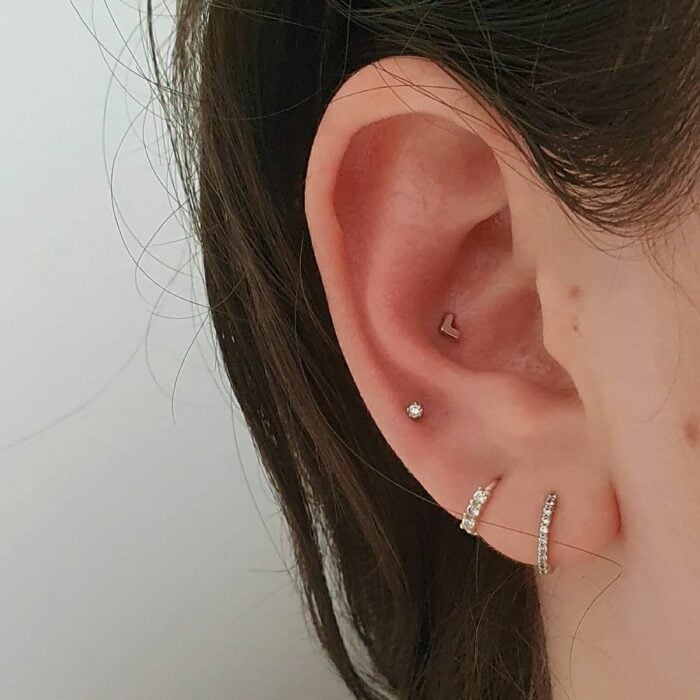 Chica con pequeños  pendientes en los oídos; 13 Creativas maneras de llevar más de un piercing en el oído