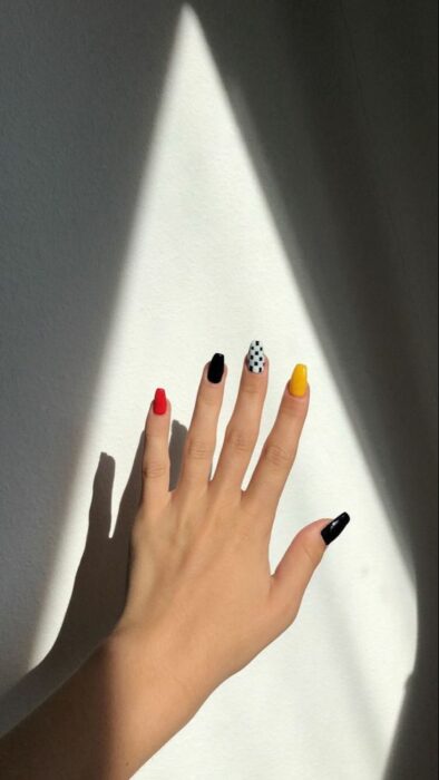 Chica con manicura en tonos rojo, amarillo, negro y blanco; 19 Manicuras estilo arcoíris a las que no te podrás negar