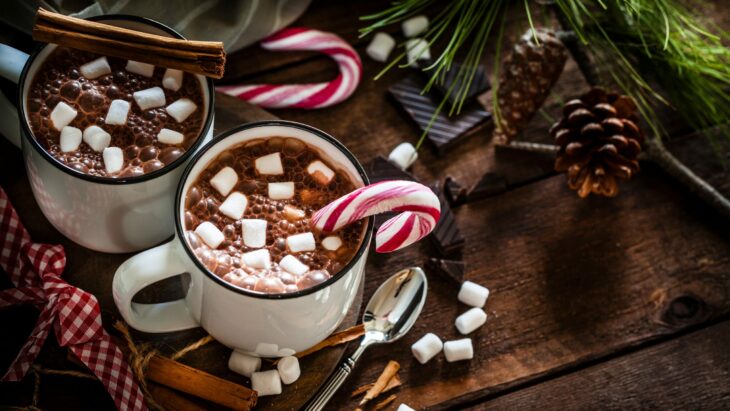 Taza de chocolate oscuro decorado con bombones y un bastón de caramelo