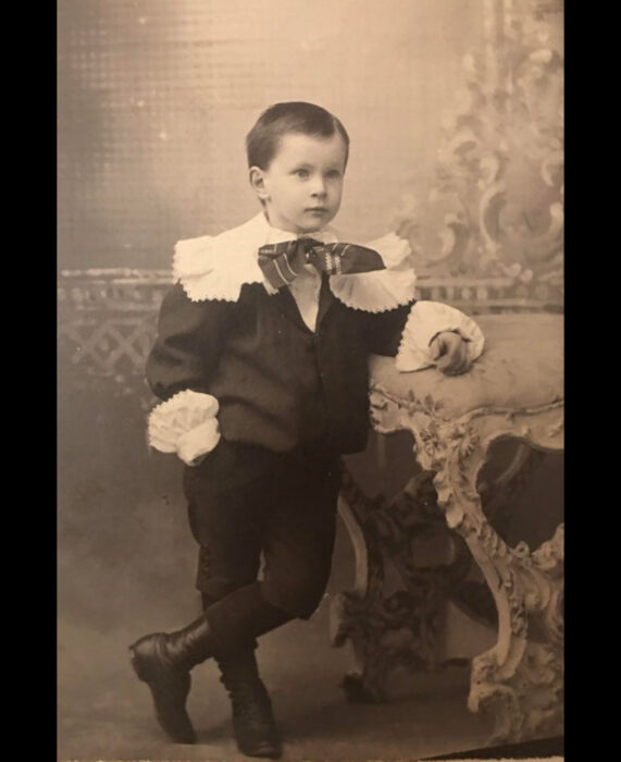 Foto vintage, fotografía antigua color blanco y negro de niño con traje antiguo, traje con holanes y botas