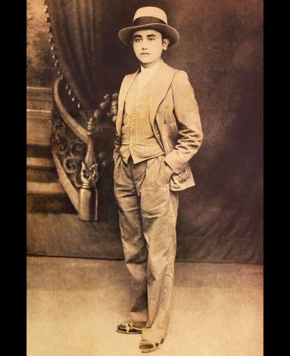 Foto vintage, fotografía antigua en color sepia de joven con traje elegante, sombrero, camisa, chaleco, saco, pantalones de vestir, con las manos en las bolsas