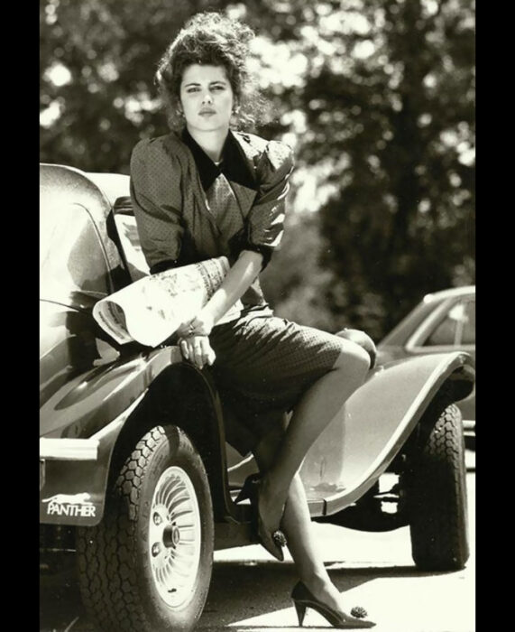 Foto vintage, fotografía antigua en color sepia, mujer con vestido de puntos recargada en un auto vintage