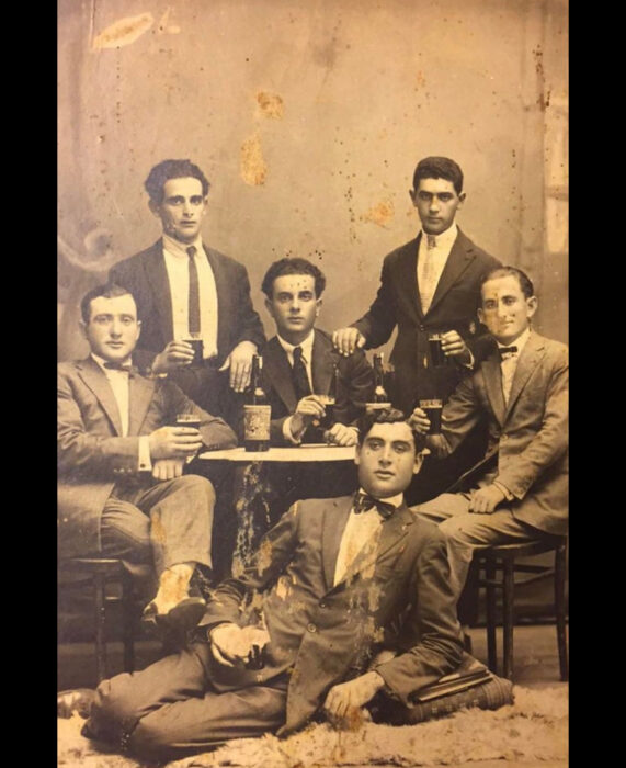 Foto vintage, fotografía antigua en color sepia de hombres con traje sentados en una mesa bebiendo