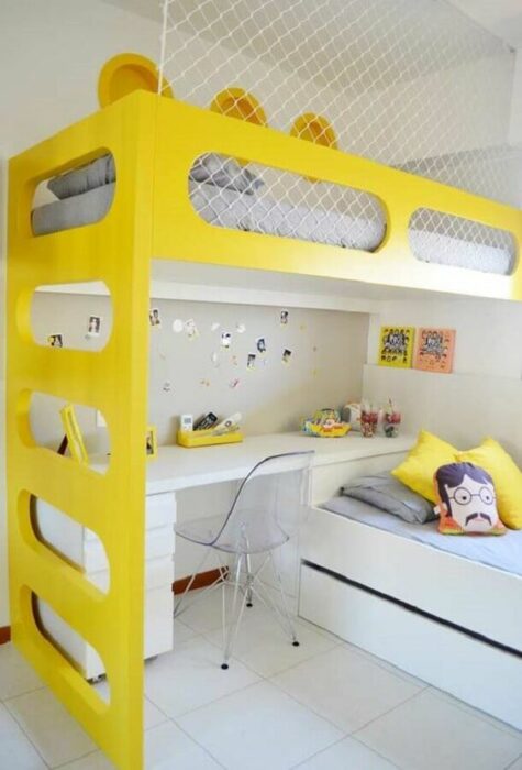 Habitación con paredes blancas con cama de dos pisos con mueble amarillo con la parte de abajo con un escritorio y la parte de arriba un colchón gris 