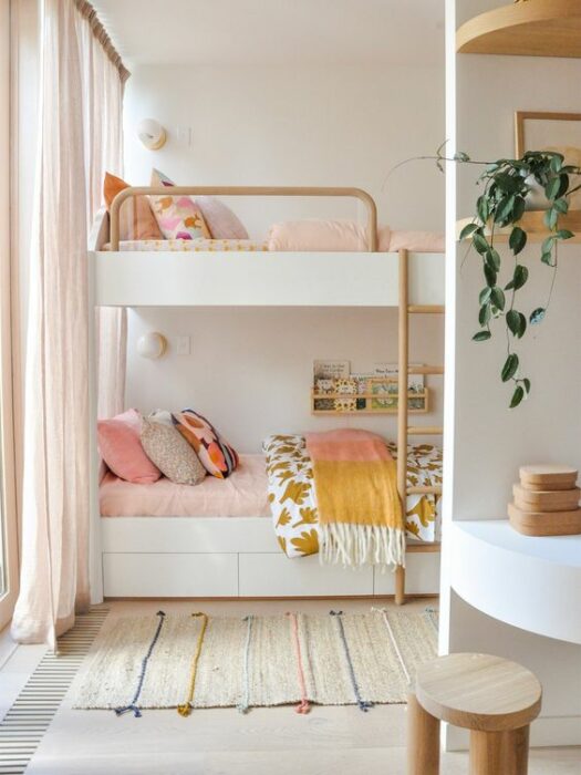 Habitación blanca con cama de dos pisos con mueble blanco y cobijas rosas