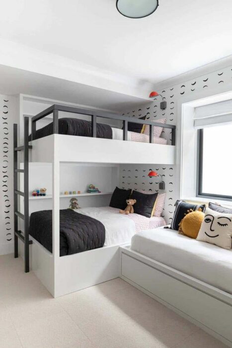 Habitación blanca con detalles negros en la pared con una cama de dos pisos con escaleras negras y cobijas blancas con negro