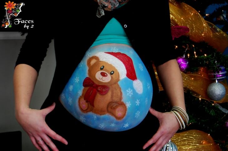 Chica con la pancita pintada con un oso navideño; Ideas para pintar tu panza de embarazada este diciembre