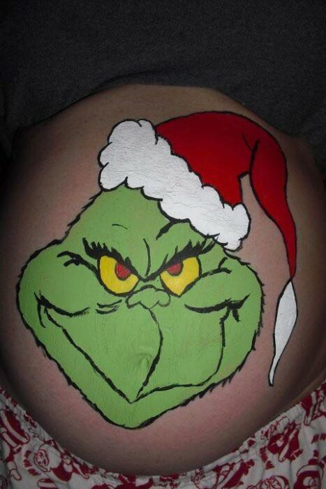 Chica con la pancita pintada de El Grinch; Ideas para pintar tu panza de embarazada este diciembre