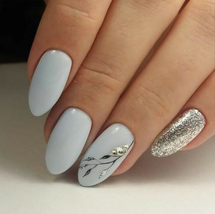 Chica con un diseño de uñas de color blanco con un toque de plateado y dorado