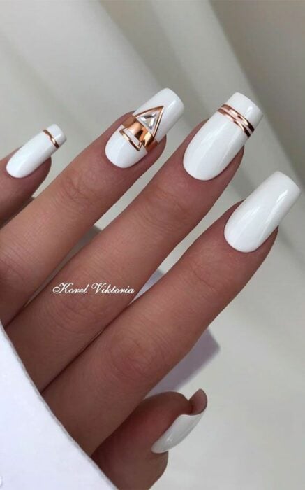 Chica con un diseño de uñas de color blanco con un toque de plateado y dorado