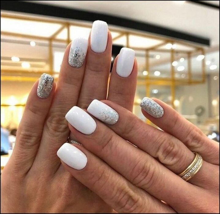 Chica con un diseño de uñas de color blanco con un toque de plateado y dorado