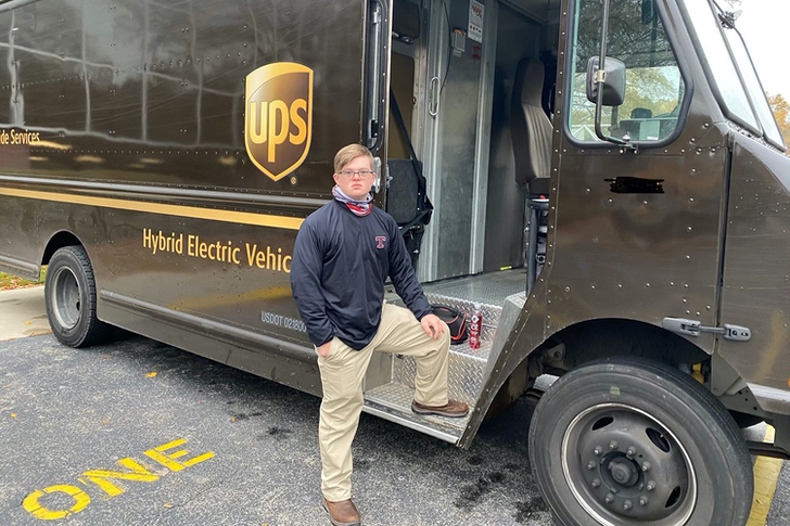 Jake Pratt con su uniforme de UPS posando en su camión repartidor