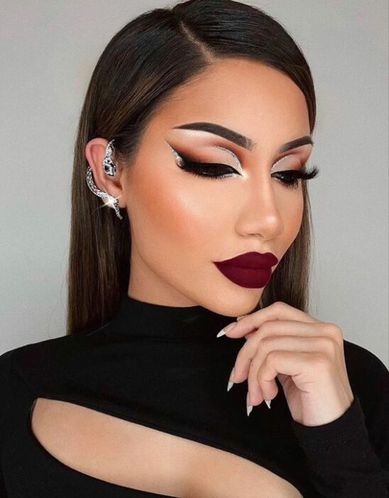 Chica con maquillaje de delineado doble, sombras doradas, labial en vino; Maquillajes para celebrar Navidad