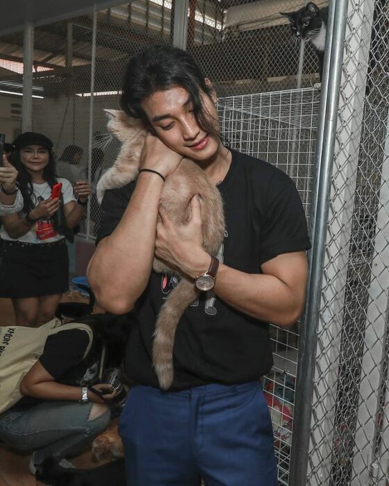 Paing Takhon con playera negra abrazando a un gato café claro