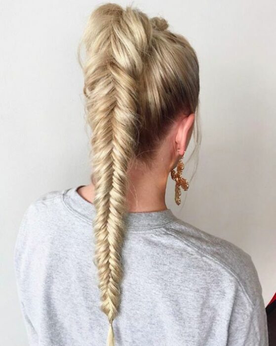 Chica de cabello rubio con una coleta alta y el cabello en trenza de espiga