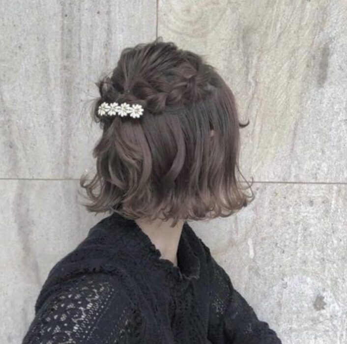 Chica de cabello negro corto, con trencitas y un broche sosteniéndolas