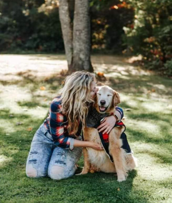 Perros sonriendo; perrito viejito golden retriever con canas y su dueña abrazándolo en el parque