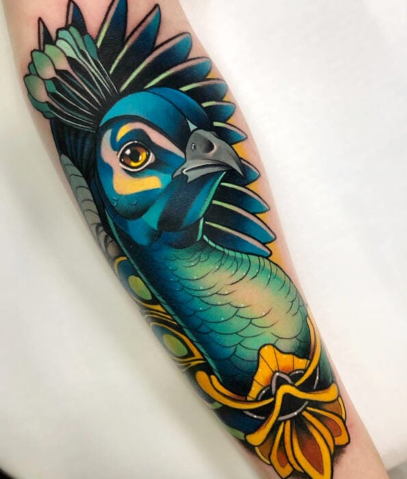 Tatuaje bonito y femenino de ave en el brazo, pájaro pavo real realista de color azul