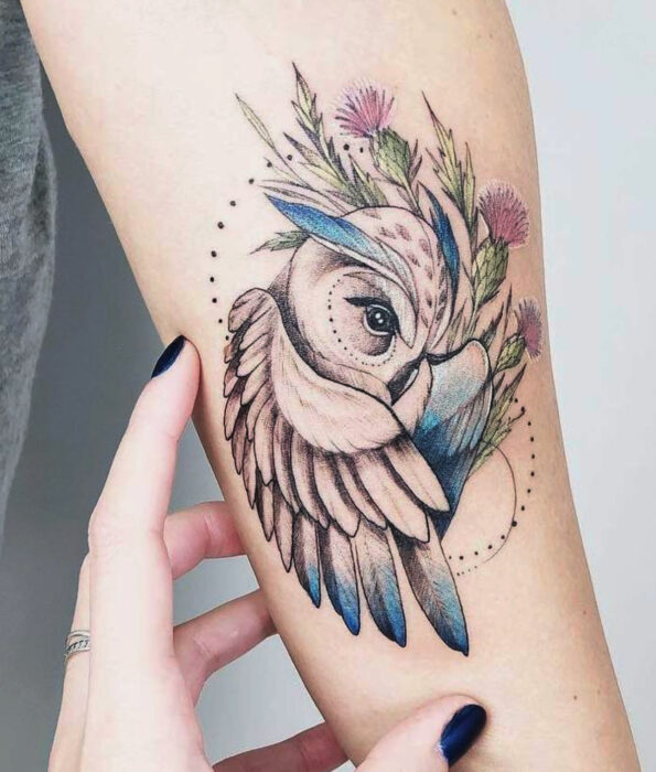 Tatuaje bonito y femenino de ave en el brazo, pájaro búho con flores