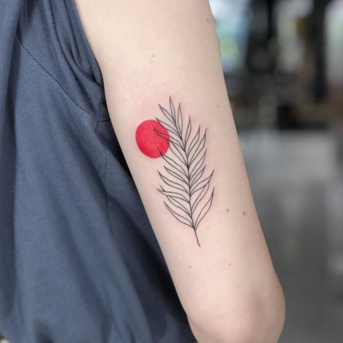 Tatuajes bonitos, pequeños y femeninos; tatuaje de hoja con círculo rojo en el brazo