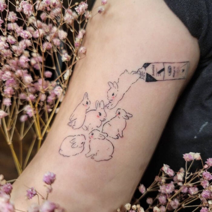 Tatuajes bonitos, pequeños y femeninos; tatuaje de conejos tiernos saliendo de un bote de pintura al óleo en el brazo