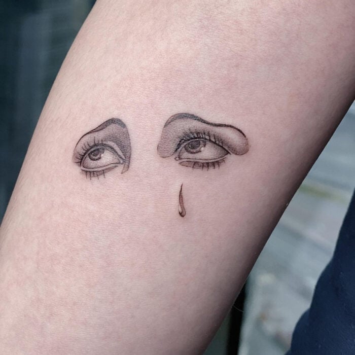 Tatuajes bonitos, pequeños y femeninos; tatuaje de ojos de mujer llorando en el brazo