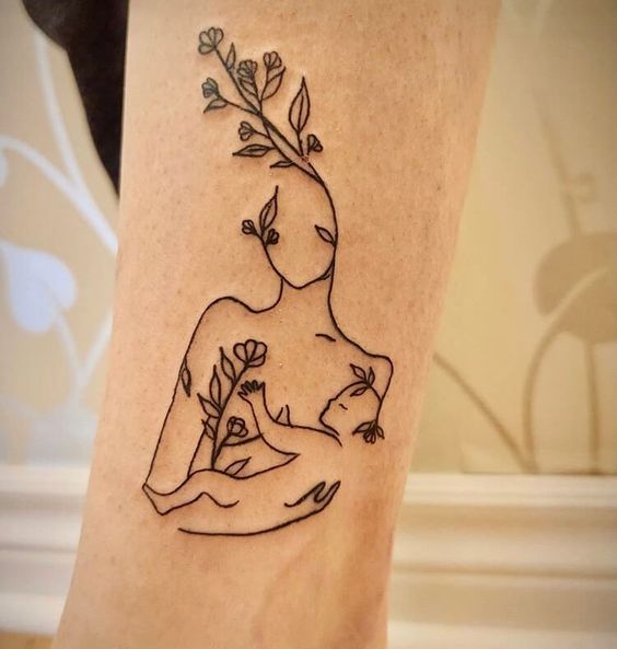 Tatuaje en el brazo de la silueta de una mamá cargando a un bebé