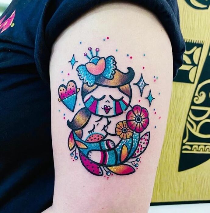 Tatuaje colorido en el brazo de madre amamantando a su hijo