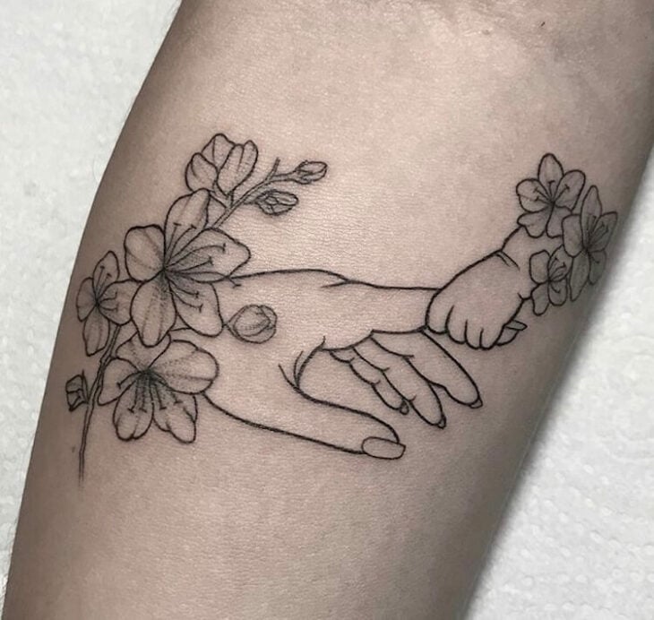 Tatuaje en el brazo de manita de bebé sosteniendo el dedo de su mamá
