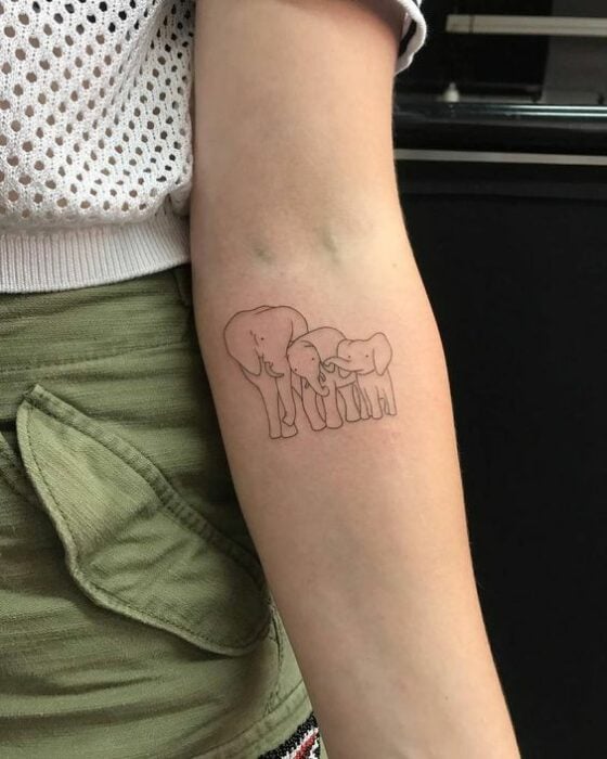 Tatuaje en el brazo con tinta negra de mamá elefante con sus dos elefantitos