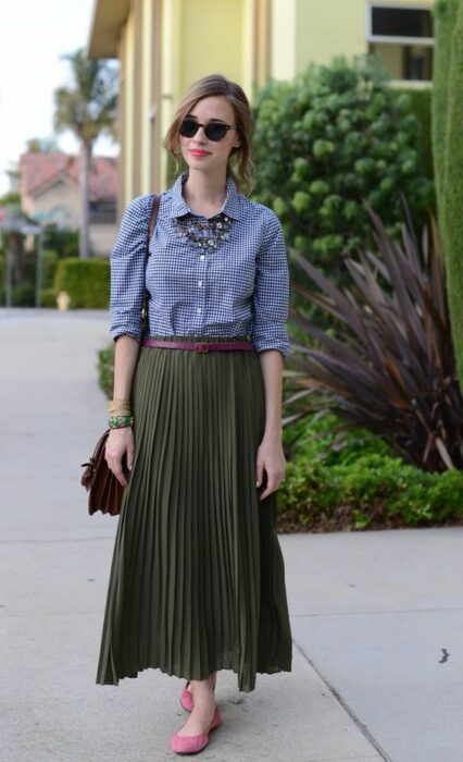 Chica usando maxi falda color verde army con flats rosas, cinturon café, camisa de mezclilla y bolso de mano