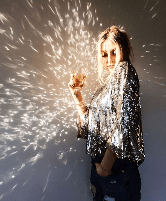 chica rubia usando una blusa plateada metálica con mangas largas abombadas y jeans a la cintura