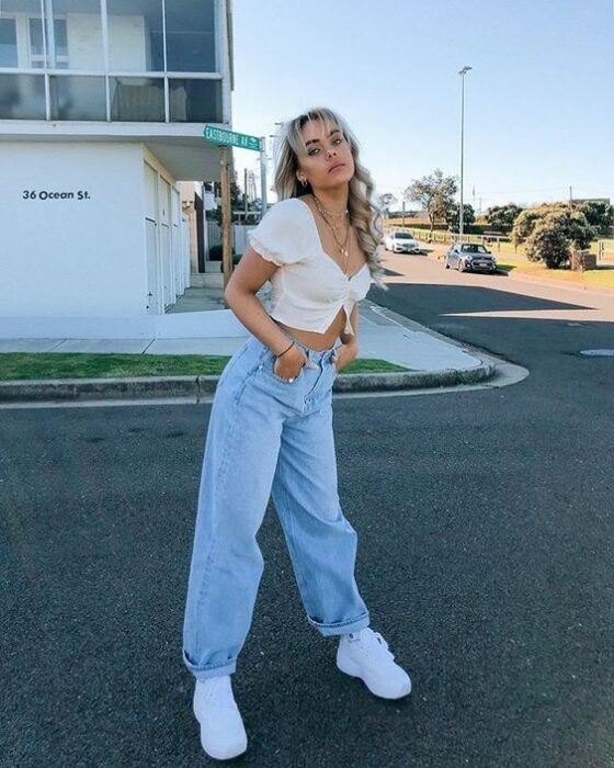 chica con jeans azules holgados y crop top blanco13 Ideas para usar pantalones holgados sin perder el estilo