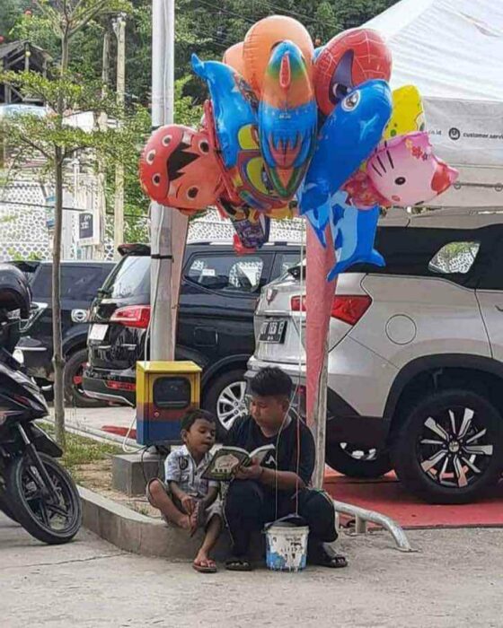 Niño le enseña a leer a su hermanito en la calle