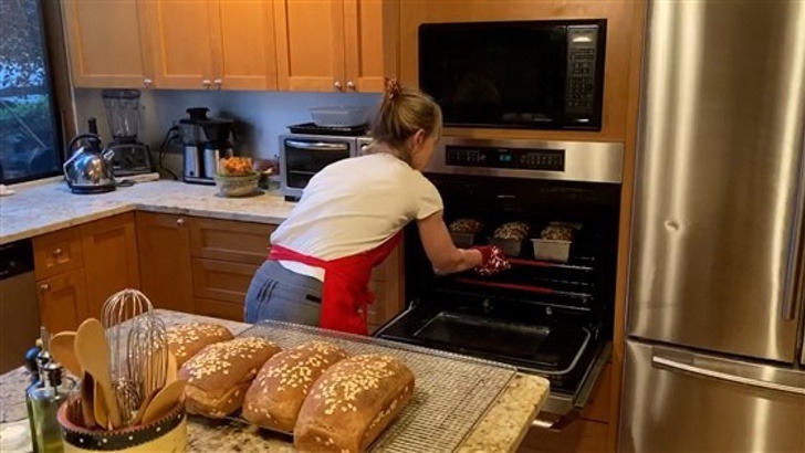 Chica horneando pan casero en el horno de su cocina 