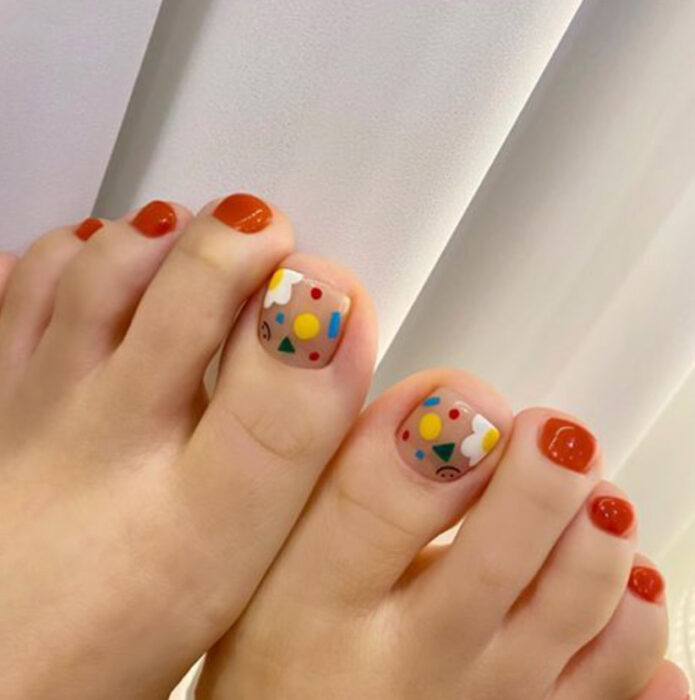 Pedicura en colores naranja y azul, amarillo y blanco