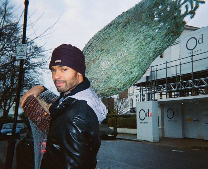 Actor Regé-Jean Page cargando un árbol de Navidad