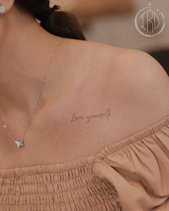 Tatuaje de palabra "love yourself" en la clavícula 