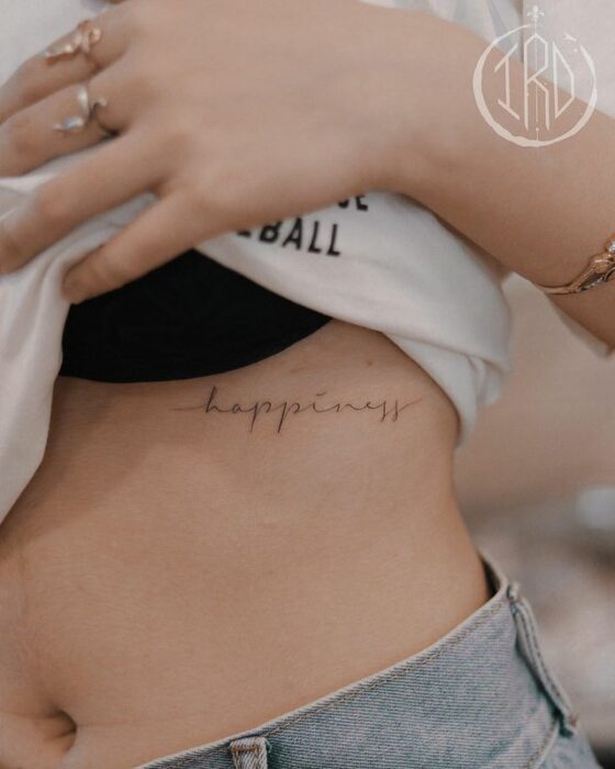 Tatuaje de palabra "hapiness" en las costillas