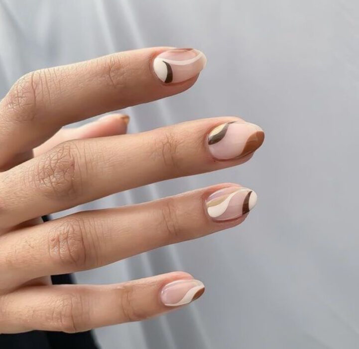 Manicura con diseño en base nude con líneas blancas, cafés y verde olivo