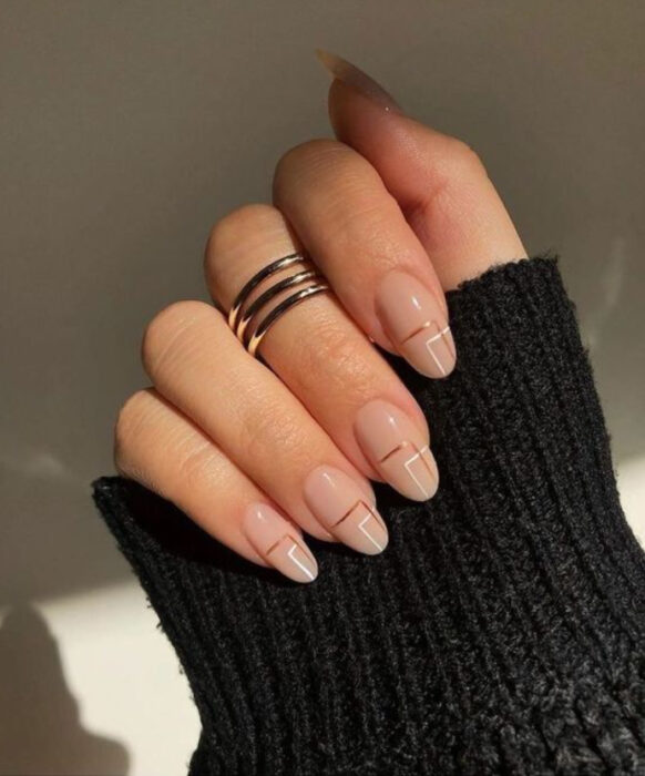 Manicura con diseño de líneas doradas y base color nude