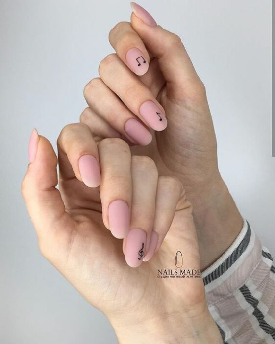 Manicura con diseño de notas musicales y base rosada