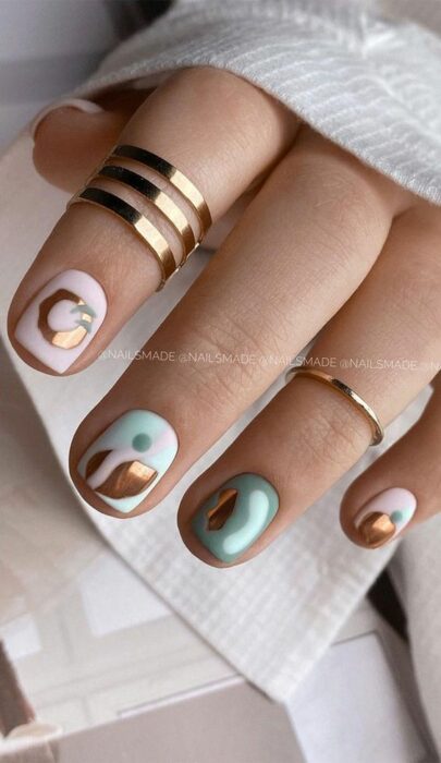 Manicura con diseño de figuras en color dorado con base en tonos neutros