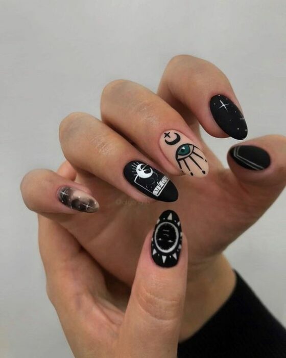 chica con manicura en tonos negro y pastel con estampados blancos;  Uñas para chicas que aman el ocultismo