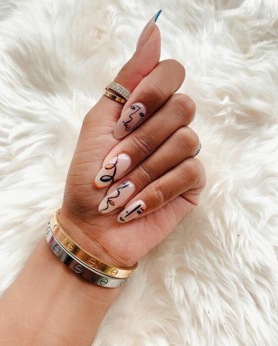 Chica con manicura stiletto en color nude con decorado de pinturas