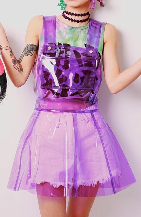 Chica posando de pie con una vestido de plástico transparente color morado 