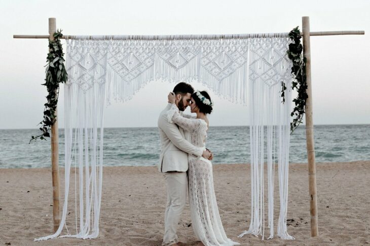 Pareja de novios casándose en la playa con el mar de fondo 