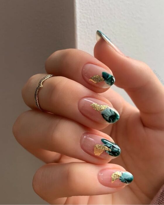 Uñas elegantes ovaladas con punta decorada con efecto azul y dorado