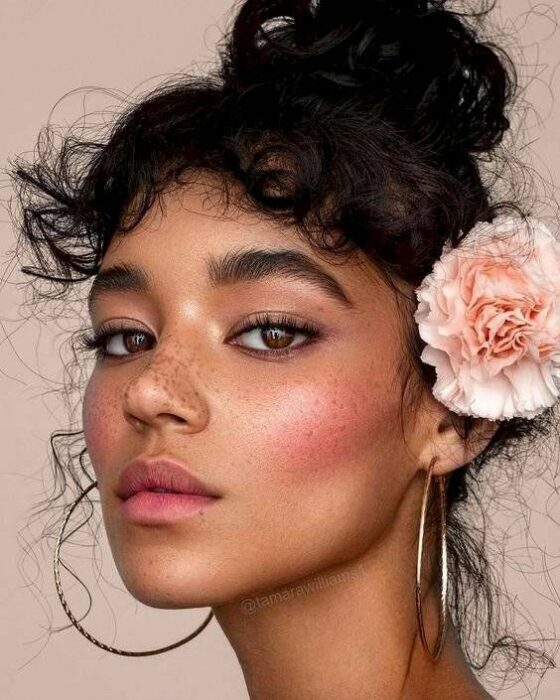 Chica de cabello negro peinada con un moño alto decorado y una flor y fleco