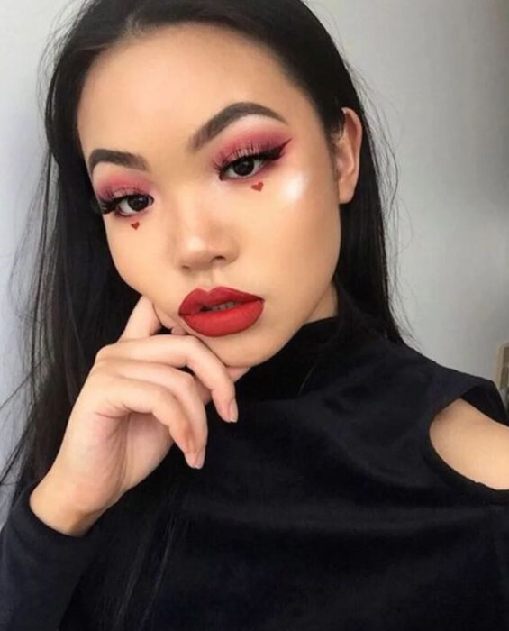 Maquillaje inspirado en San Valentín en colores rojo y guina con corazones debajo de los ojos